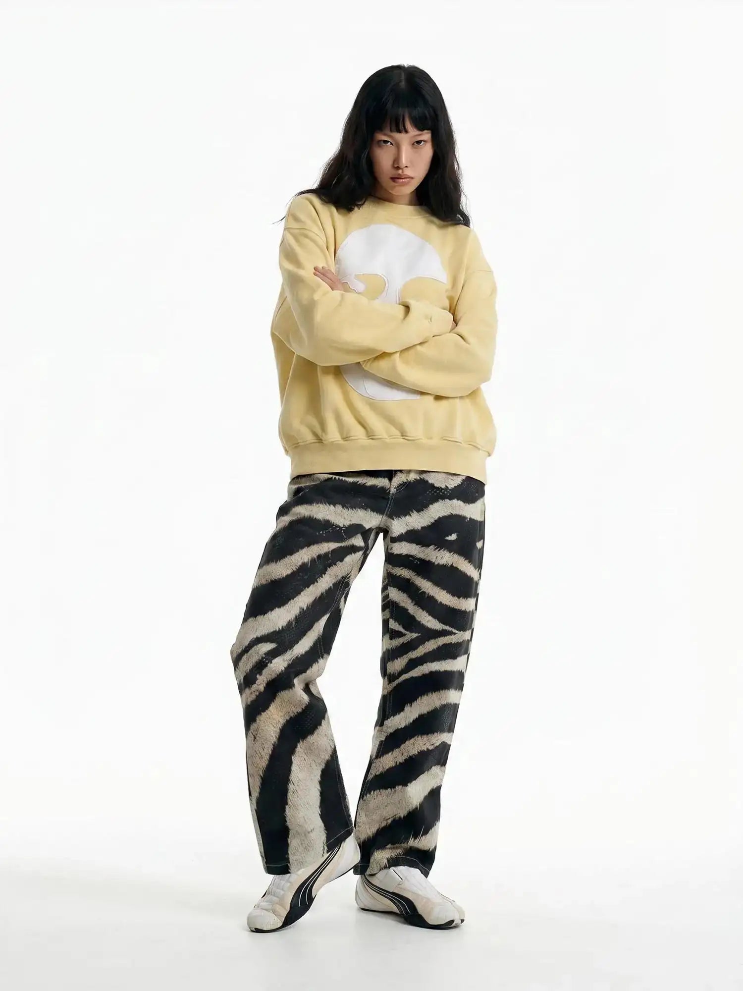 Pale yellow loose fit sweatshirt featuring abstract white face design styled with zebra pants